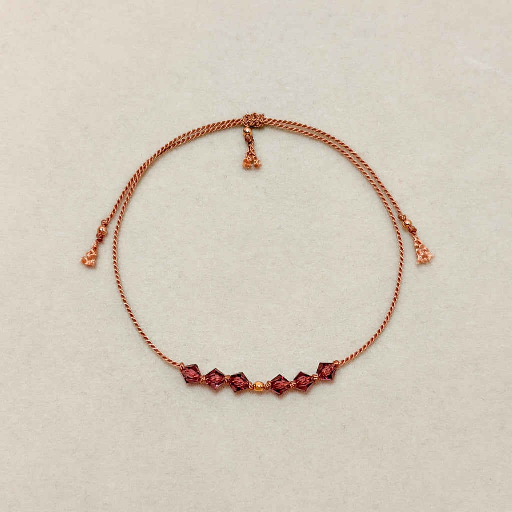 Quiet Strength adjustable bracelet with Amethyst crystals, beige silk cord, and gold-filled details on a soft ivory velvet background.