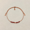 Quiet Strength adjustable bracelet with Amethyst crystals, beige silk cord, and gold-filled details on a soft ivory velvet background.