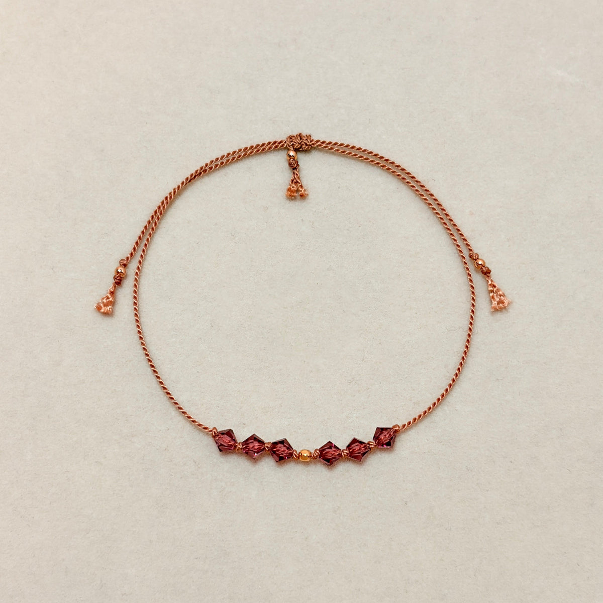 Quiet Strength adjustable bracelet with Amethyst crystals, beige silk cord, and gold-filled details on a soft ivory velvet background.