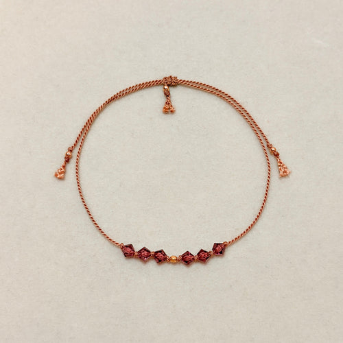 Quiet Strength adjustable bracelet with Amethyst crystals, beige silk cord, and gold-filled details on a soft ivory velvet background.
