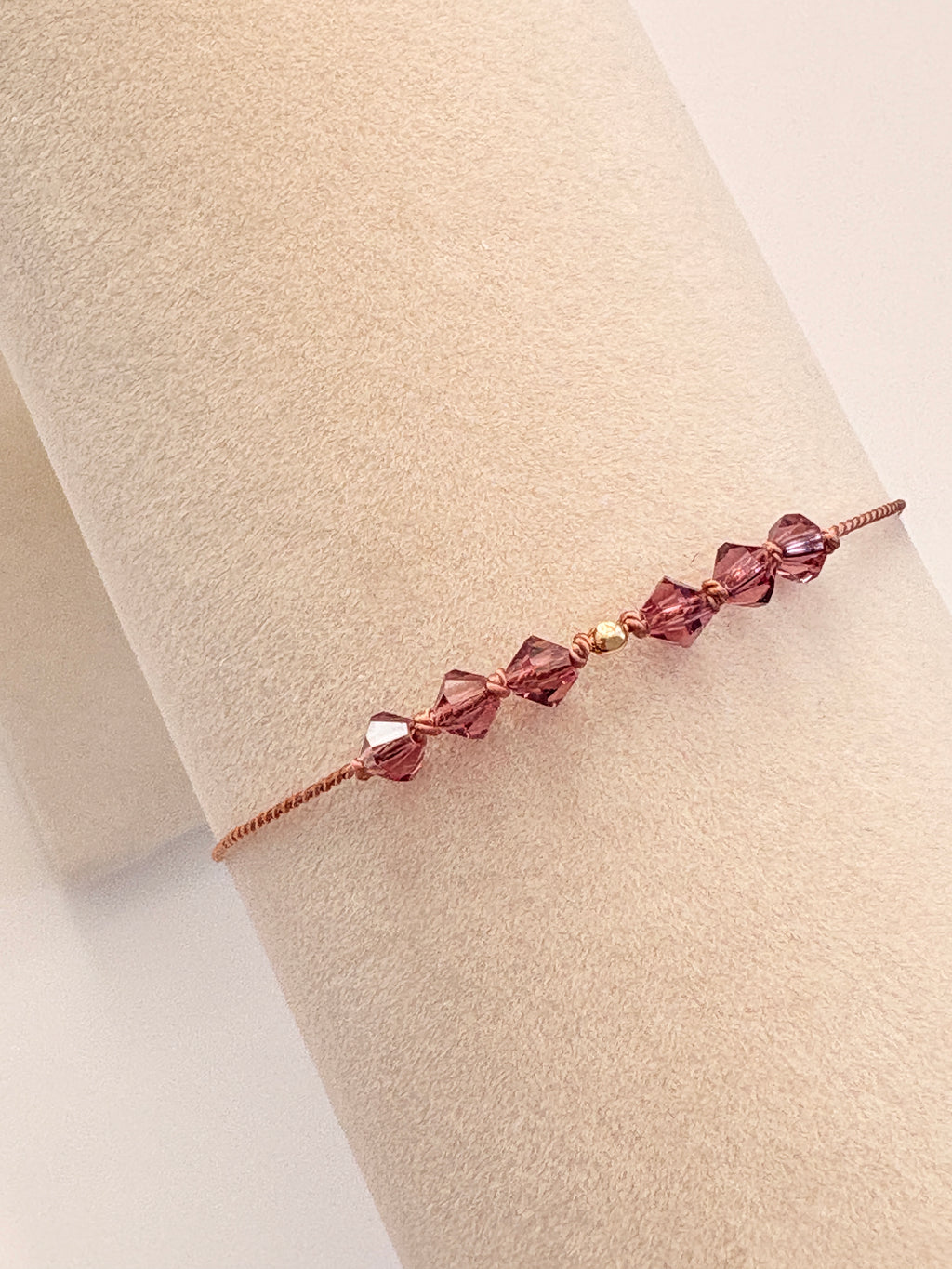 Quiet Strength bracelet displayed on a beige cream T-stand, showing Amethyst crystals and gold-filled details.