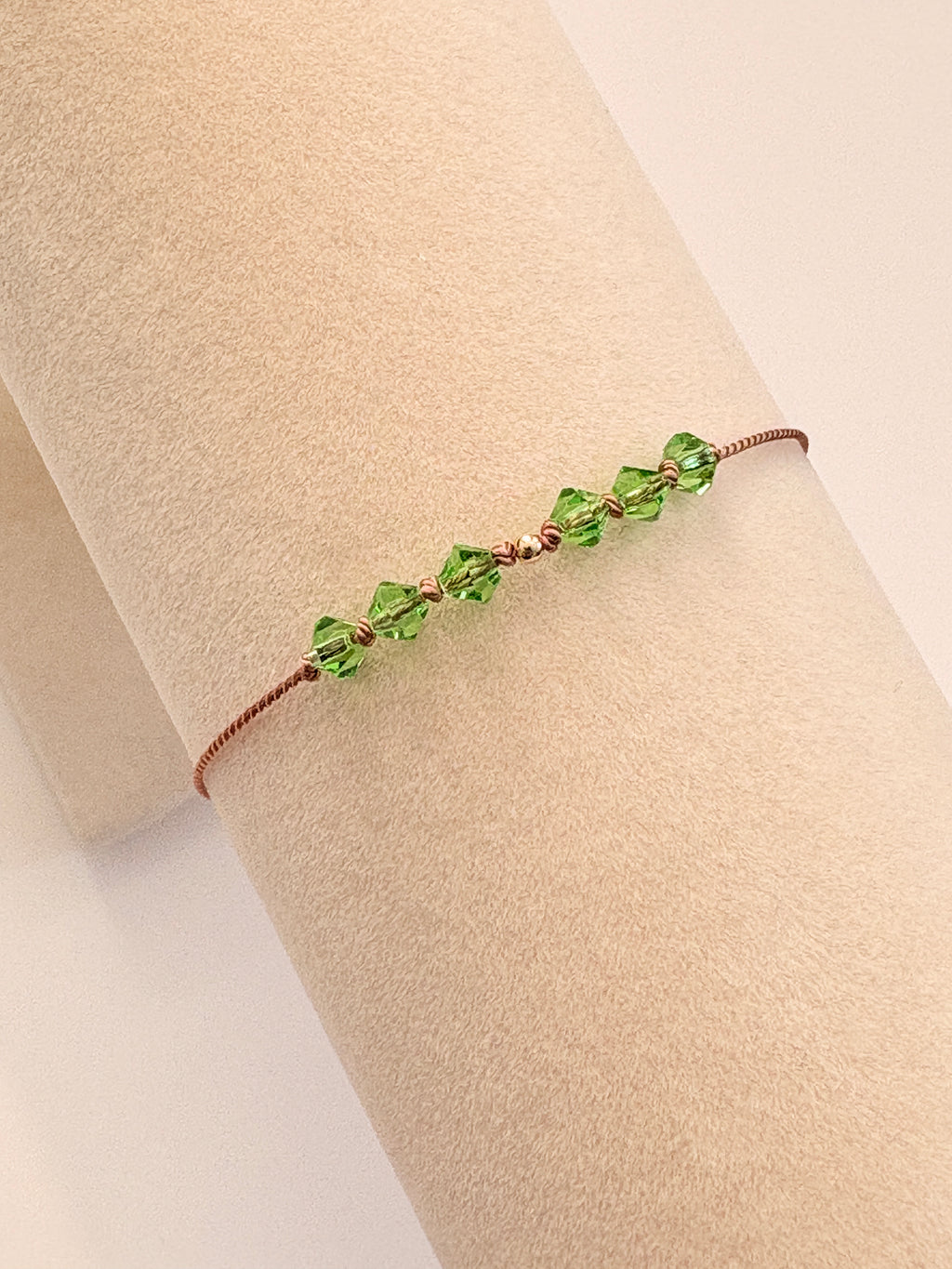 Renewal bracelet displayed on a beige cream T-stand, showing Peridot crystals and gold-filled details.