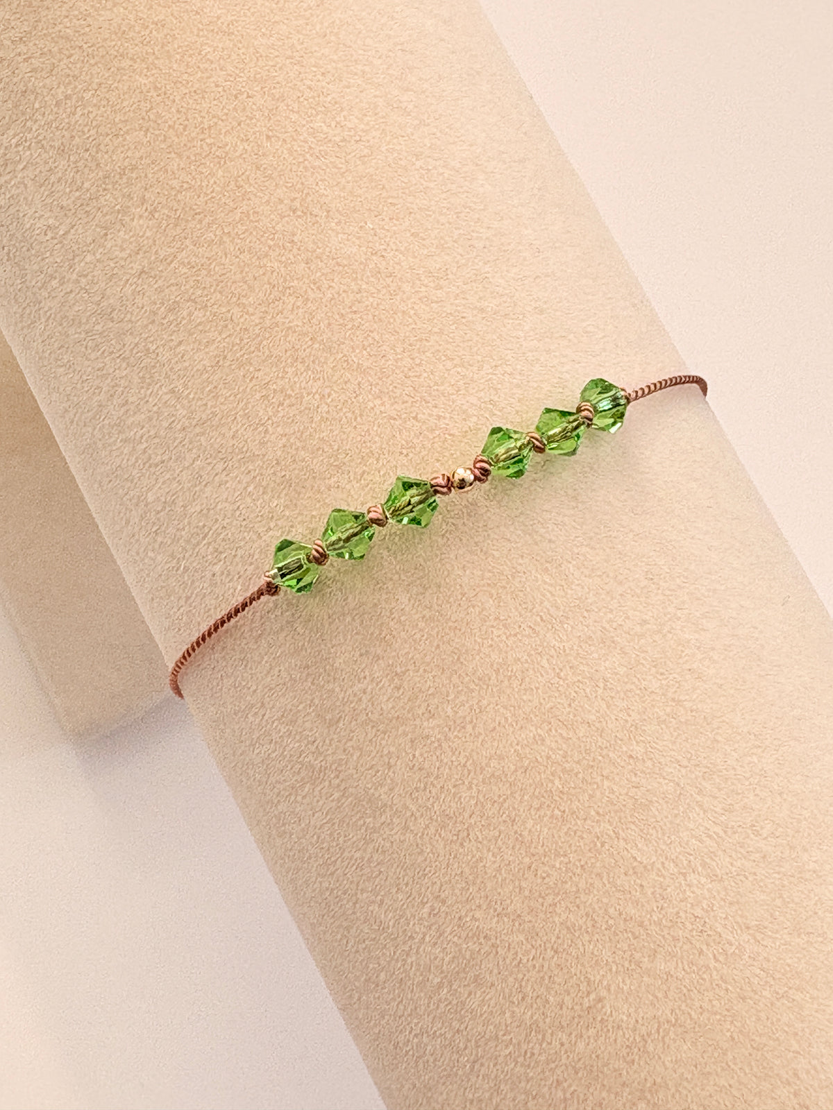 Renewal bracelet displayed on a beige cream T-stand, showing Peridot crystals and gold-filled details.