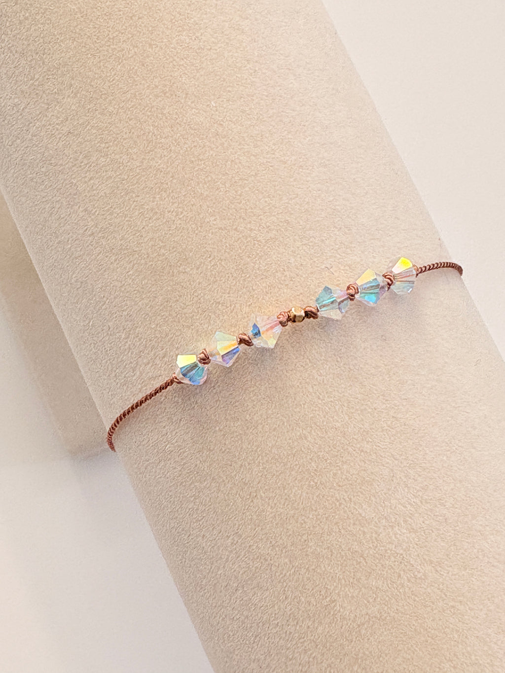 Eternal Hope bracelet displayed on a beige cream T-stand, showing iridescent Crystal AB crystals and gold-filled details.