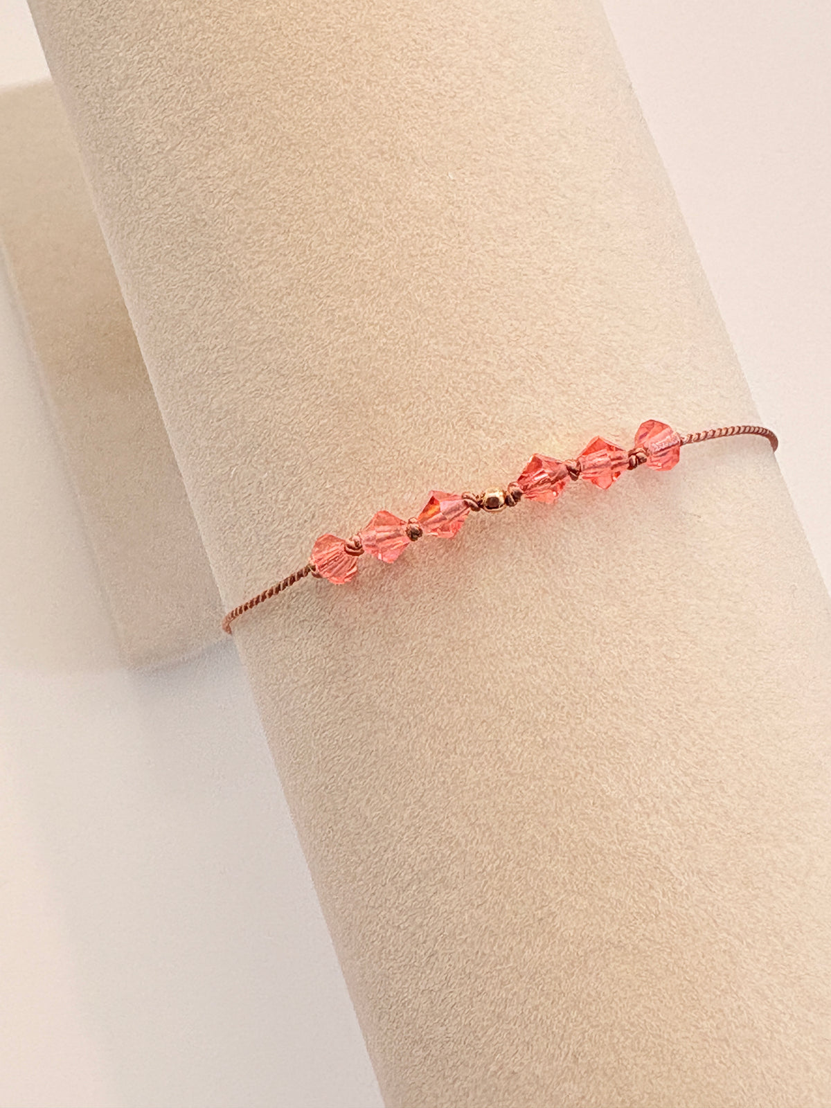 Golden Memory bracelet displayed on a beige cream T-stand, showing Rose Peach AB crystals and gold-filled details.