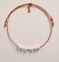 Eternal Hope adjustable bracelet with iridescent Crystal AB crystals, beige silk cord, and gold-filled details on an ivory background.