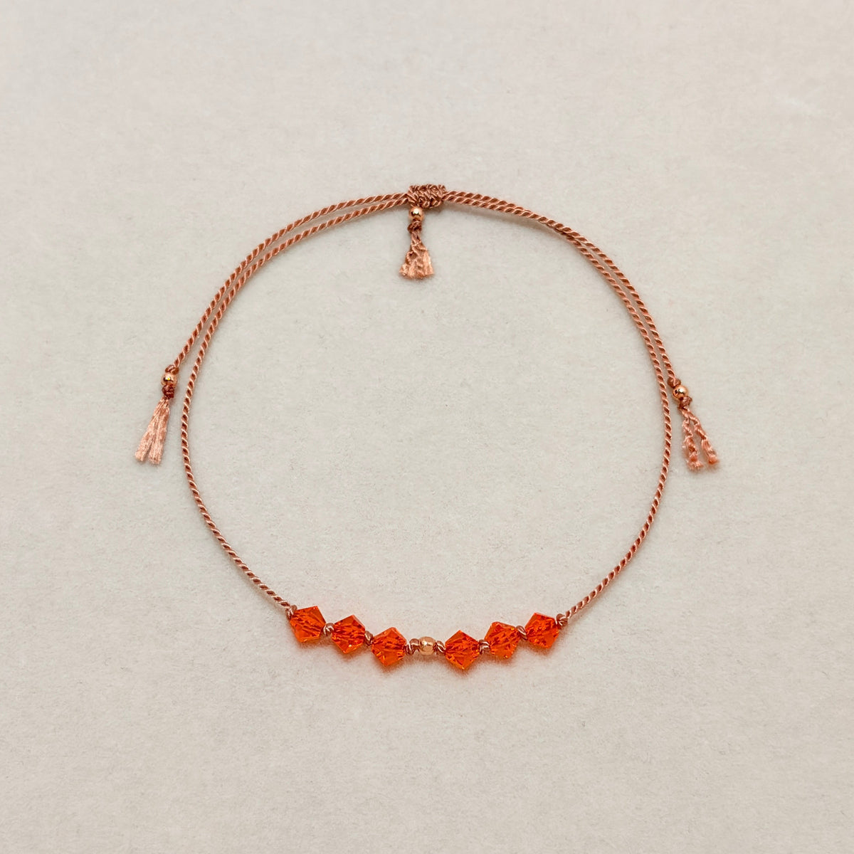 Radiant Hope adjustable bracelet with vibrant Sun crystals, beige silk cord, and gold-filled details on a soft ivory velvet background.